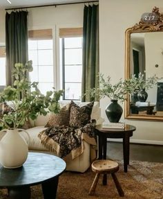 a living room filled with furniture and a large mirror on the wall above it's windows