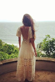 a woman in a white dress looking out at the ocean