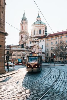 a train is coming down the tracks in front of some old buildings and church spires