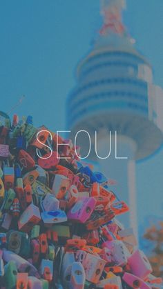 the words seoul are surrounded by many colorful objects in front of a tall building with a blue sky behind it