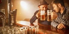 two men sitting at a bar drinking beer