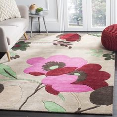 a living room area with a couch, chair and flower rug on the hardwood floor