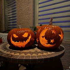 two carved pumpkins sitting on top of a table