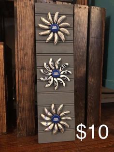 three metal sunflowers sitting on top of a wooden shelf