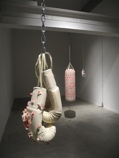 two boxing gloves hanging from chains in an empty room with other items on the floor