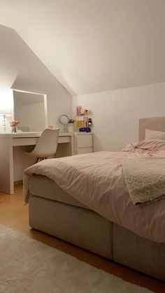 a bedroom with a bed, desk and mirror in the corner on top of it