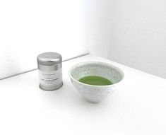 a white bowl filled with green liquid next to a container