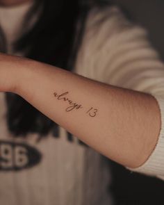 a person with a tattoo on their arm that says happy 13 in cursive writing