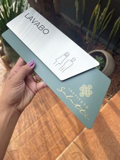 a person holding up two business cards in front of a house with cacti and succulents