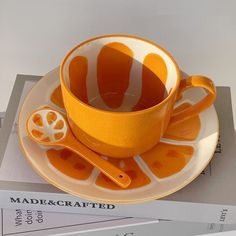 an orange cup and saucer sitting on top of a stack of books next to each other