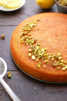 there is a cake with pistachios on it and a spoon next to it