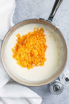 a pan filled with food sitting on top of a white table next to silver spoons