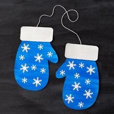 two blue mittens with white snowflakes on them hanging from a string ornament