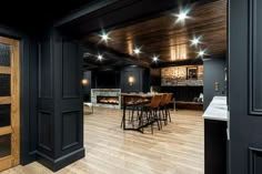 an open kitchen and dining room with wood flooring, black walls and ceiling lights