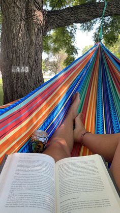 a person laying in a hammock reading a book