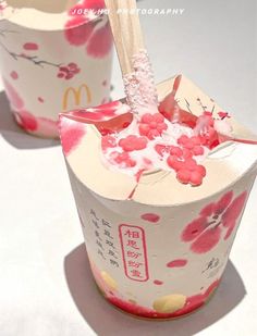 two cups with pink and white designs on them, one has a spoon in it