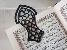 an open book with arabic calligraphy on the pages and a candle holder in the middle