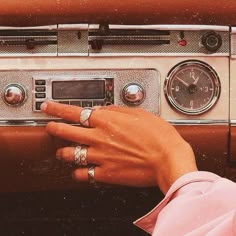 a woman's hand on the dashboard of an old fashioned car with two rings