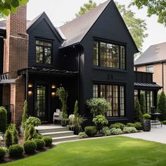 a large black house with lots of windows and plants in front of the entrance to it