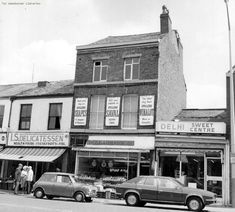 an old black and white photo of cars parked in front of stores