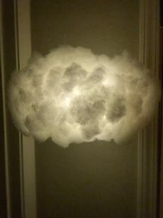 a cloud is floating in the air over a door way with a light shining on it