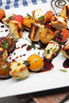 grilled vegetables on skewers with sauce drizzled over them and garnished with parsley