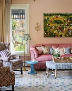 a living room filled with furniture and a painting hanging on the wall above it's windows