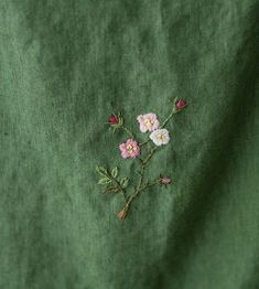 a green cloth with pink flowers embroidered on it