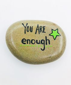 a rock with the words you are enough written on it and a green star in the middle