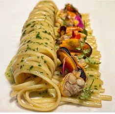 two pastas with sauce and vegetables are on a white tablecloth, one is cut in half