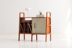 a wooden cabinet with books on it and a lamp in the corner next to it