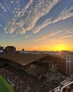 the sun is setting over a stadium full of people in it's stands as the sun sets