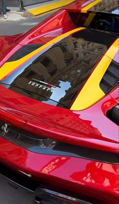 a red sports car with yellow stripes parked on the street