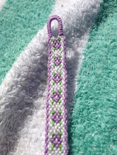 a purple and green beaded bracelet laying on top of a rug