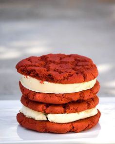 three red and white cookies with ice cream stacked on top of each other in front of the camera