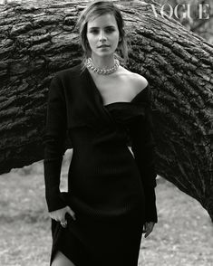 a woman standing next to a tree wearing a black dress and choker necklaces