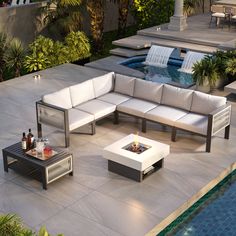 an outdoor living area with couches, tables and pool in the backround