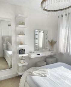 a bedroom with white furniture and mirrors on the wall