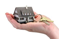 a hand holding a small house with keys in it