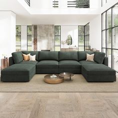 a large green couch sitting in the middle of a living room next to tall windows