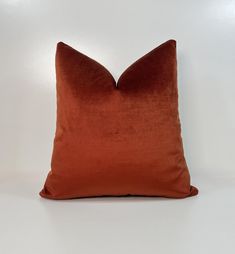 an orange pillow on a white background with no one in the photo to describe it