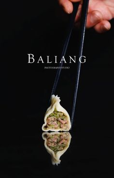 a person holding two chopsticks with food on top of it and the words balig above them