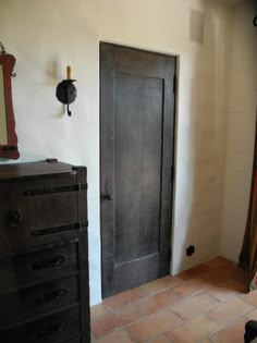 a room with a black door and a mirror on the wall next to a dresser