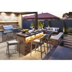 an outdoor kitchen with bar seating and grill