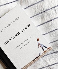 the book chasing slow is laying on top of a bed with blue and white striped sheets