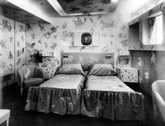 an old photo of two beds in a room with floral wallpaper on the walls