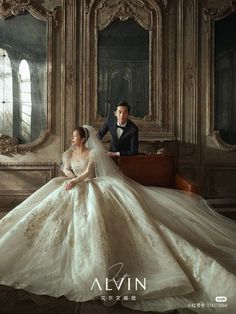 a man and woman in wedding dresses sitting on a couch with an ornate mirror behind them