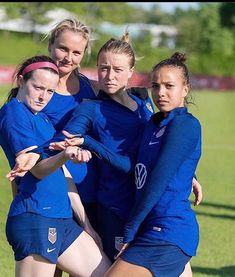 a group of young women standing next to each other on top of a soccer field