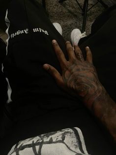 a man with tattoos on his arm and hand holding onto a black t - shirt