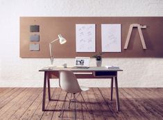 a desk with a lamp and pictures on the wall above it, in front of a white brick wall